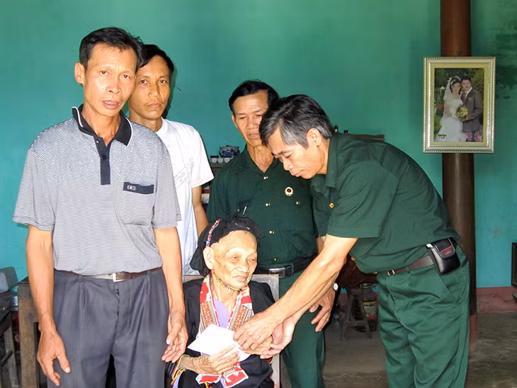 CCB Trần Quốc Mạnh (ngoài cùng, bên phải) tặng sổ tiết kiệm của Hội CCB huyện Hoành Bồ cho mẹ liệt sĩ ở thôn Phủ Liễn, xã Đồng Sơn, huyện Hoành Bồ. (Ảnh do nhân vật cung cấp)