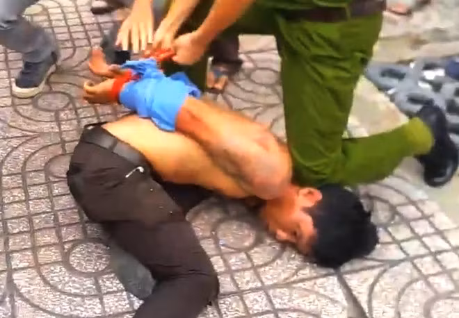 Nam bảo vệ bị công an bắt giữ sau khi giật dây chuyền bất thành. Ảnh: Cắt từ clip.