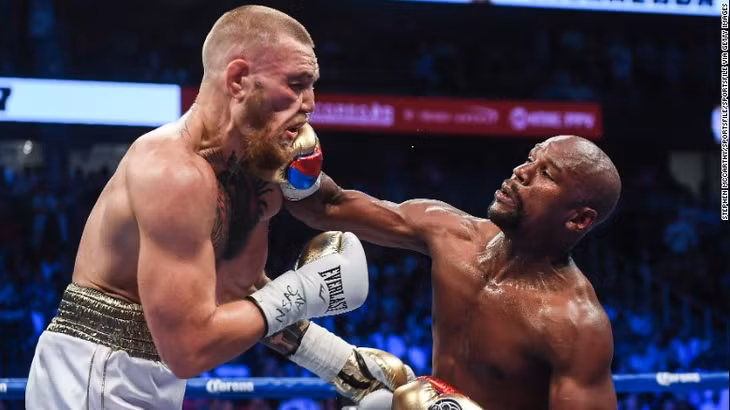 Mayweather (phải) tung đòn vào mặt đối thủ McGregor trong trận đấu.