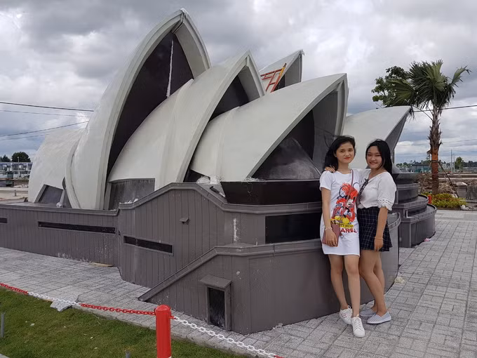 Các bạn trẻ háo hức tạo dáng bên mô hình nhà hát Opera Sydney có kiến trúc độc đáo giống hình con sò. Bản gốc của nó là nơi biểu diễn nghệ thuật nằm ở bến cảng Sydney, Australia.