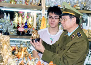 Cán bộ Đội QLTT số 6 TP Uông Bí kiểm tra một gian hàng bán sản phẩm lưu niệm tại xã Thượng Yên Công.