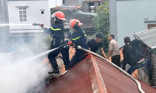 Lính cứu hỏa&nbsp; trèo lên mái nhà căng sức dập lửa.