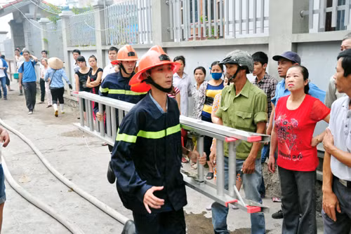 Lực lượng cảnh sát PCCC mang thang sắt tìm cách trèo lên nóc nhà tiếp cận hiện trường.