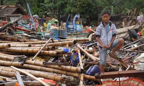 Một thiếu niên đứng trên đống đổ nát ở tây đảo Java chiều 24/12. Ảnh: AFP.