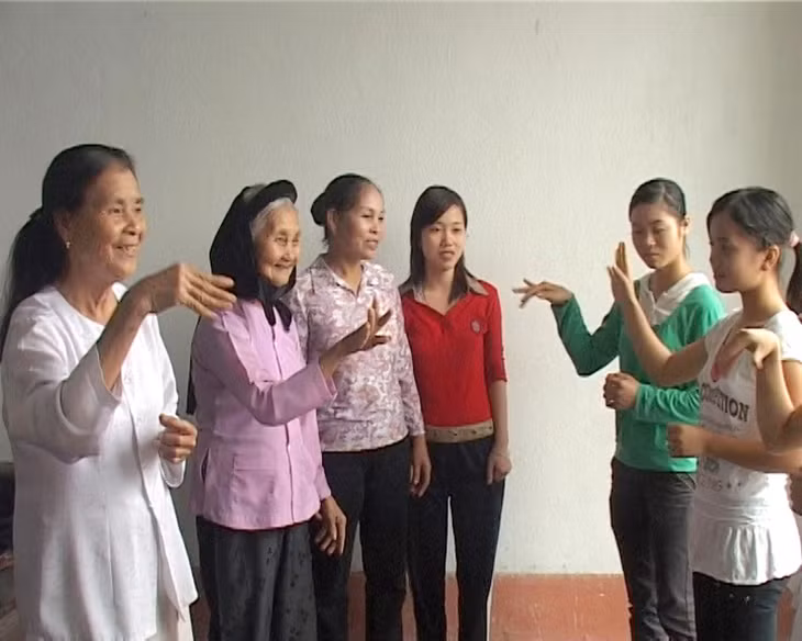 Nghệ nhân ưu tú Đặng Thị Tự, xã Đầm Hà, huyện Đầm Hà dạy con, cháu trong xã hát, múa nhà tơ. Ảnh: Phòng Văn hóa thể thao huyện Đầm Hà cung cấp.