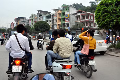 Thanh niên, học sinh đi hàng 3, không đội mũ bảo hiểm.