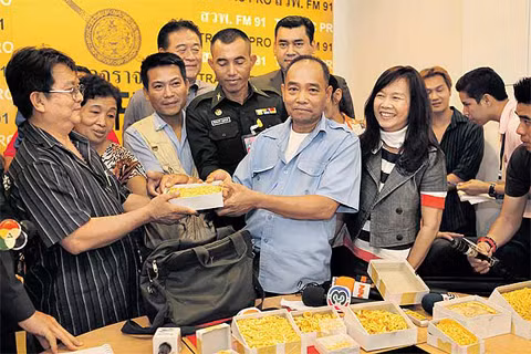 Người lái xe (phải) trao trả những hộp vàng cho khách hàng tại sở cảnh sát. Ảnh:Bangkok Post
