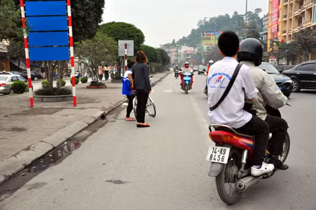 Học sinh trường THPT chuyên Hạ Long ngồi sau xe máy không đội mũ.