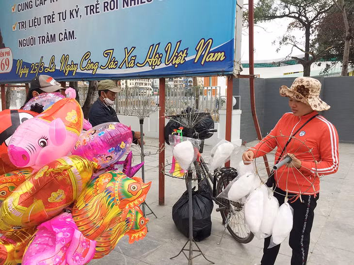 Chị Nguyễn Thị Dung, quê ở Thanh Hóa, bên gánh hàng rong bán bóng bay, kẹo bông.