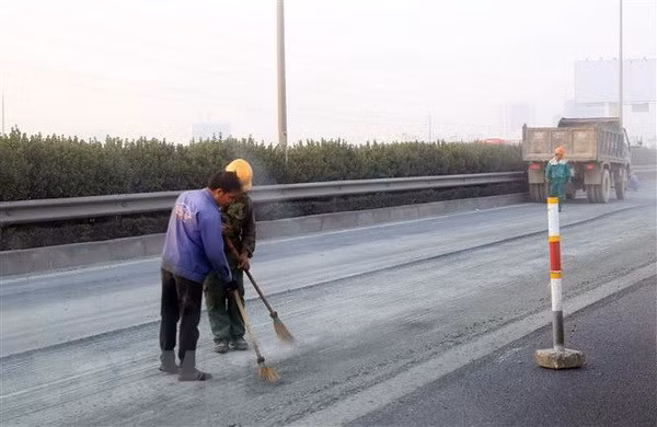 Vệ sinh mặt đường để chuẩn bị thảm nhựa. (Ảnh: Huy Hùng/TTXVN)
