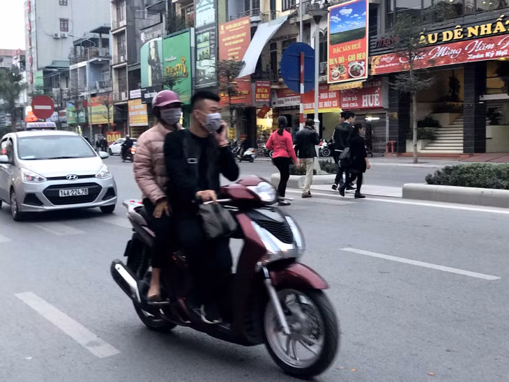 Không đội mũ, vừa đi vừa nghe điện thoại bất chấp nguy hiểm.