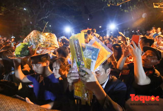 Phía ngoài đền Trần người dân treo nhau vào làm lễ.