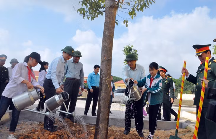 Các đại biểu dự lễ phát động cùng các em học sinh tham gia trồng cây xanh tại khu vực Ban CHQS huyện Hoành Bồ.