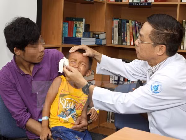 Bác sỹ Trần Châu Thái thăm khám cho bệnh nhi Y Khương Mlo sau phẫu thuật. (Ảnh: Phương Vy/TTXVN)