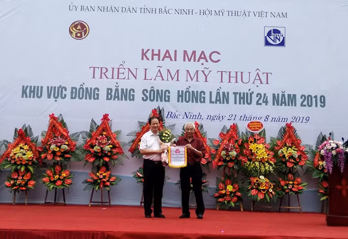 Lãnh đạo Hội VHNT Quảng Ninh nhận cờ luân lưu đăng cai tổ chức triển lãm vào năm 2020.