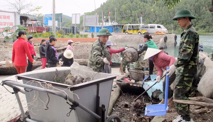 Các chiến sĩ Đồn Biên phòng Ngọc Vừng cùng nhân dân dọn vệ sinh môi trường tại khu vực cảng tàu thôn Ngọc Nam, xã Ngọc Vừng. Ảnh: Dương Trường.