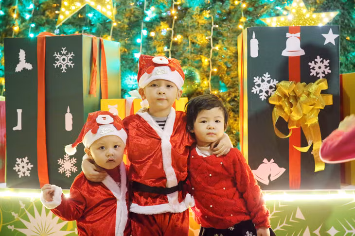 Bé chụp hình bên cây thông Noel.