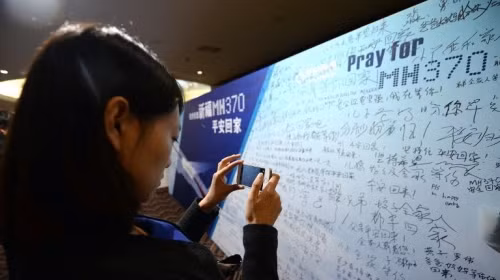 Một phụ nữ Trung Quốc chụp ảnh lưu giữ thông tin các hành khách trên máy bay MH370 (Ảnh AFP)