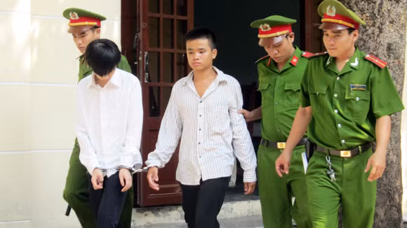  Bị cáo Luân (áo trắng) và nạn nhân Tuấn được dẫn giải sau phiên tòa