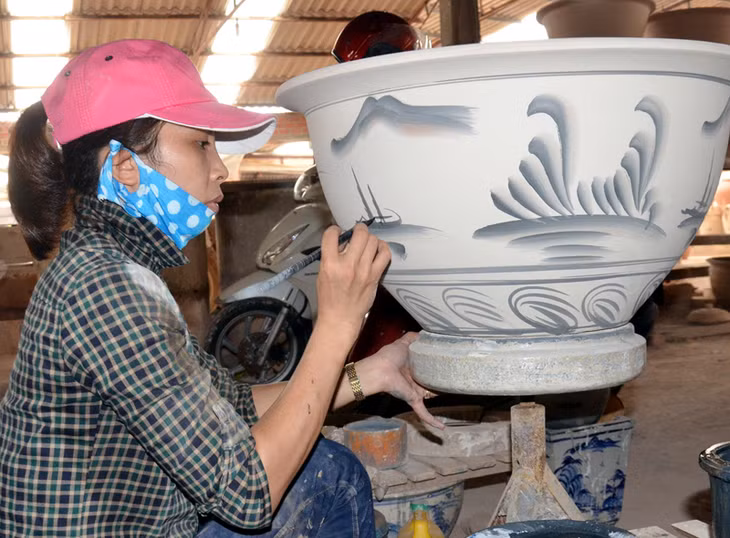 Thợ thủ công lành nghề phác hoạ những đường nét hoa văn tinh xảo trên sản phẩm gốm.
