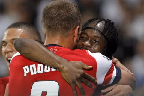 Gervinho và Podolski ôm nhau mừng những bàn thắng tối qua.