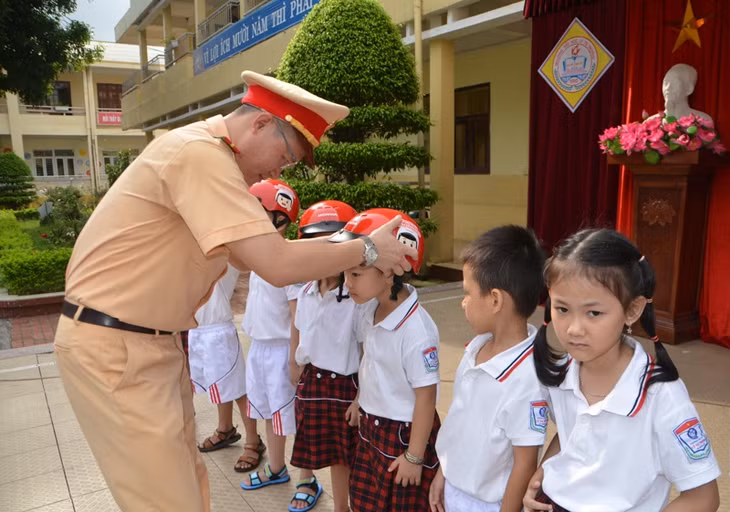Tuyên truyền luật giao thông và hướng dẫn đội mũ bảo hiểm cho học sinh lớp 1.