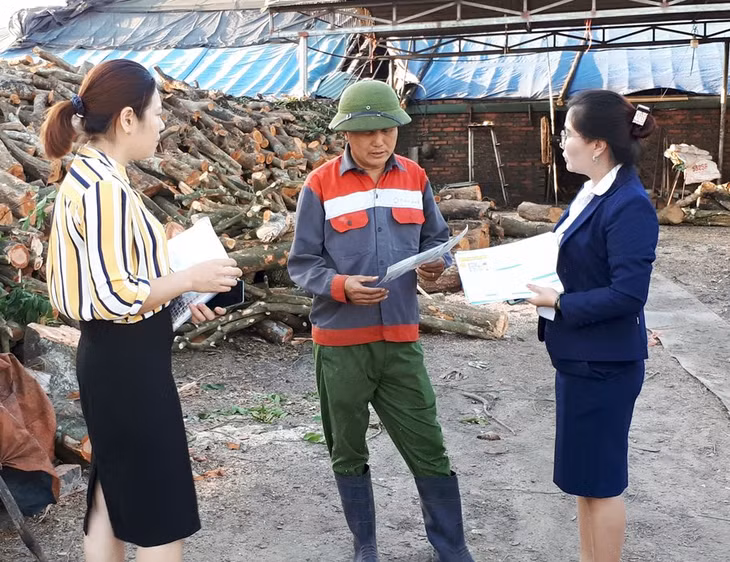 Cán bộ BHXH và Bưu điện TX Đông Triều tuyên truyền, vận động người dân tham gia BHXH tự nguyện tại xã Bình Khê (TX Đông Triều).