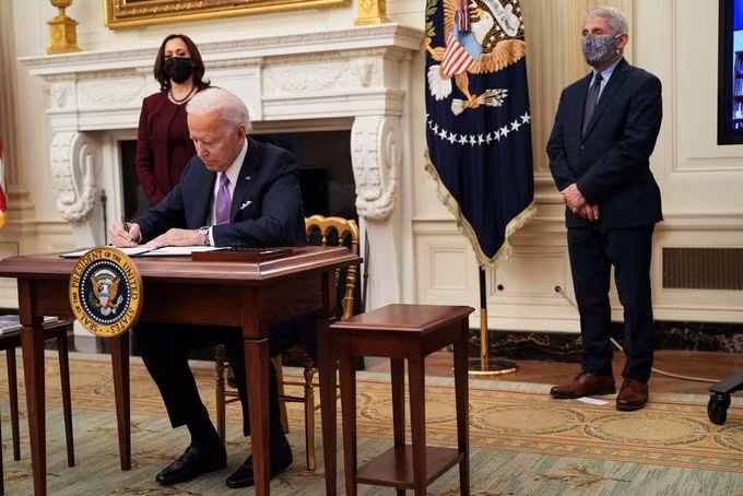 Tổng thống Mỹ Joe Biden ký một loạt sắc lệnh nhằm tăng cường phản ứng liên bang đối với Covid-19 tại Nhà Trắng hôm 21/1. Ảnh: New York Times.