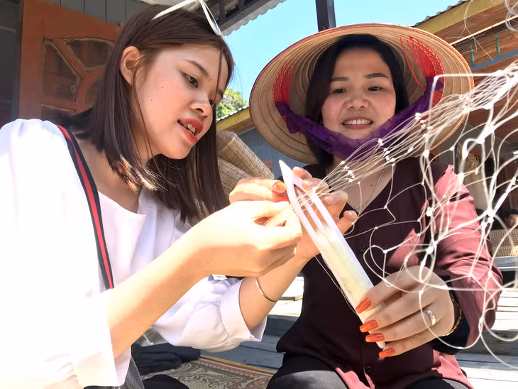 Du khách trải nghiệm đan lưới tại làng chài Cửa Vạn trên Vịnh Hạ Long.
