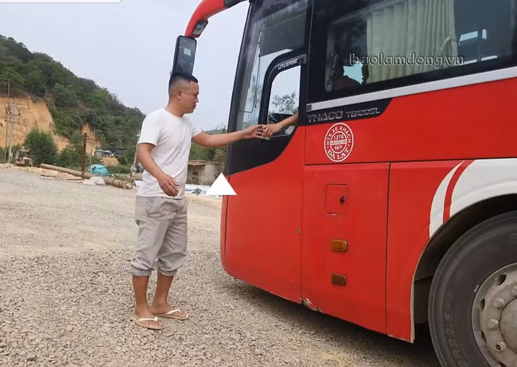 Người đàn ông nhận tiền từ chiếc xe khách giường nằm 45 chỗ để cho xe qua cầu vào sáng 19/1. Ảnh: baolamdong.vn
