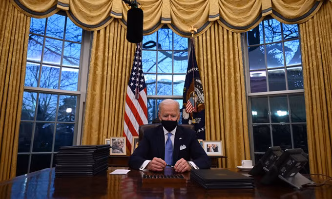 Tổng thống Mỹ Joe Biden chuẩn bị ký các sắc lệnh tại Phòng Bầu dục hôm 20/1. Ảnh: AFP.