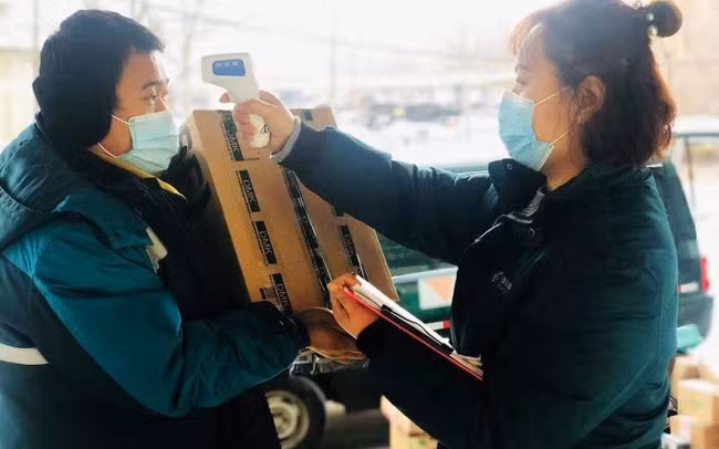Nhân viên bưu điện Đại Hưng kiểm tra thân nhiệt trước khi giao hàng. Ảnh: Báo Nhân dân
