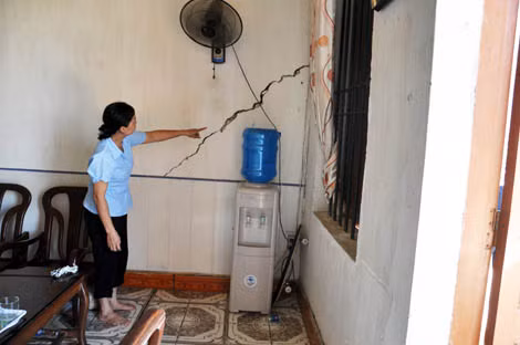 Chị Lê Thị Hậu đang chỉ về những vệt nứt tường nhà do ảnh hưởng của việc thi công tuyến kè làm sụt lở đường