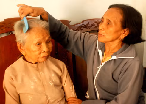 Mẹ VN anh hùng Võ Thị Khá đang được con gái là chị Trần Thị Khen chăm sóc. Ảnh: Trí Tín