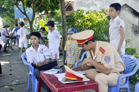 Đội CSGT Công an huyện Yên Hưng lập biên bản xử lý vi phạm đối với một đối tượng là học sinh điều khiển xe máy khi chưa đủ tuổi và chở 3.