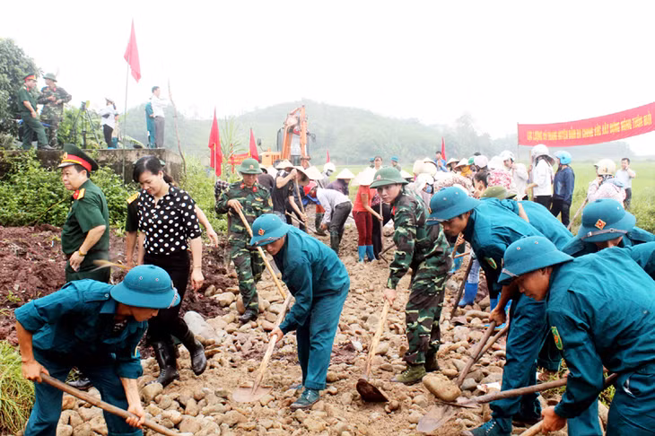 Cán bộ, chiến sĩ LLVT huyện Đầm Hà giúp người dân xã Tân Bình làm đường xây dựng nông thôn mới.