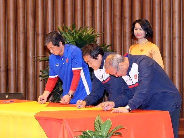 Lãnh đạo, huấn luyện viên, các cầu thủ đội bóng U23 Việt Nam ký tên lên lá cờ Tổ quốc được Chủ tịch Quốc hội Nguyễn Thị Kim Ngân mang về từ Cột cờ Lũng Cú (Hà Giang). (Ảnh: Trọng Đức/TTXVN)