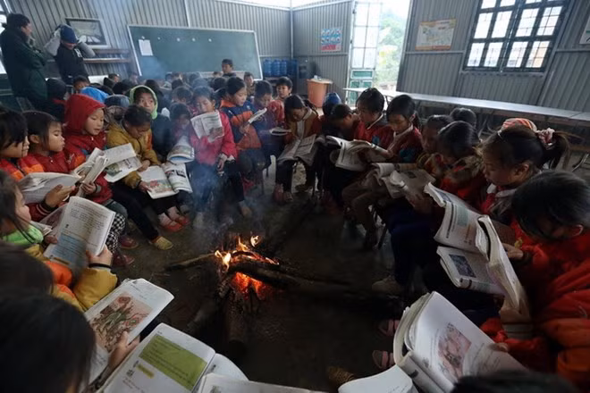 Học sinh nội trú trường Tiểu học Tỏa Tình, huyện Tuần Giáo ngồi ôn bài bên đống lửa sưởi ấm trong những ngày giá rét. (Ảnh: Phan Tuấn Anh/TTXVN)