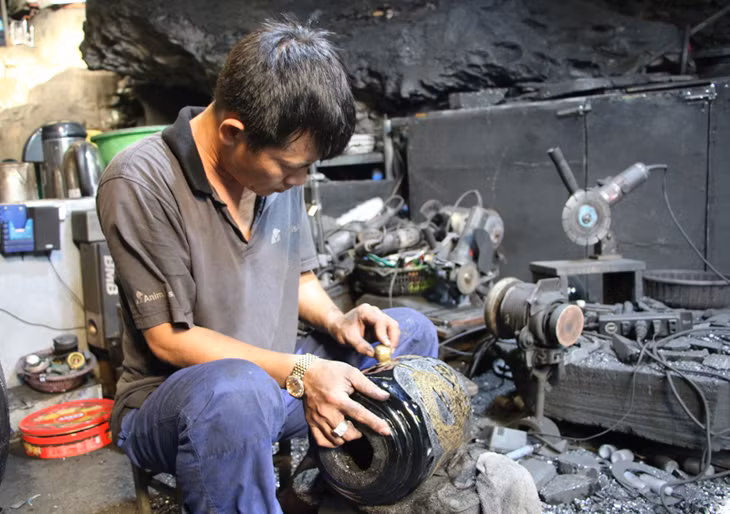 Nghệ nhân Nguyễn Tuấn Quyết tỉ mẩn chạm khắc trang trí họa tiết cho bình hoa làm bằng than đá.