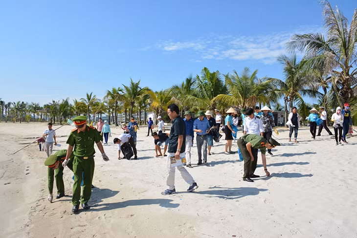 Đoàn thanh niên Công an tỉnh, Ban Quản lý vịnh, Chi hội tàu du lịch... thu gom rác thải trên bờ biển Tuần Châu. (Ảnh: Minh Châu)