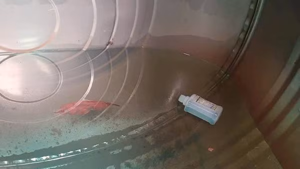 Hình ảnh chai thuốc trừ sâu trong bể nước nhà anh Sơn. (Ảnh: Nguyễn Hinh)