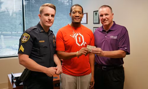 Anh Randrell Lewis, giữa, giao nộp số tiền nhặt được cho cảnh sát Dunwoody. Ảnh: Dunwoody Police