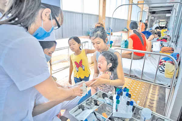 Một điều dưỡng xét nghiệm máu cho bệnh nhi sốt xuất huyết