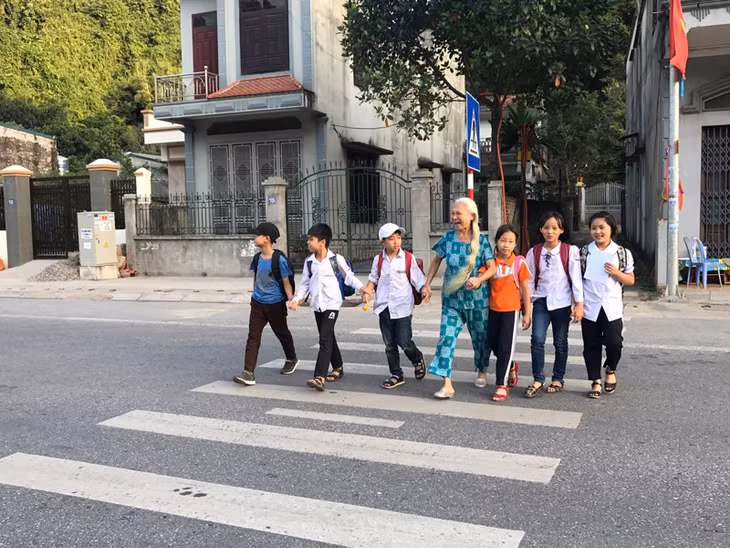Mỗi ngày bà đưa hàng chục lượt học sinh qua đường.