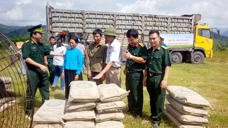 Người dân xã Đồng Tâm (Bình Liêu) phấn khởi nhận xi măng do Tổng Công ty Viễn thông Quân đội hỗ trợ. Ảnh: Trịnh Vân Anh (Ban Dân tộc tỉnh)