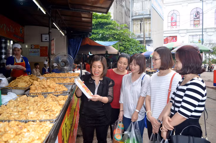 Chị Nguyễn Thị Thoan, Chủ tịch Hiệp hội Chả mực Hạ Long, đồng thời là chủ cửa hàng Thoan - Chả mực tại chợ Hạ Long I (ngoài cùng bên trái) giới thiệu sản phẩm chả mực cho du khách.