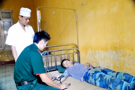 Trung tá Phạm Quang Trung, thạc sĩ - bác sĩ, Bệnh xá trưởng đảo Phan Vinh và điều dưỡng viên, thiếu uý Nguyễn Việt Hải thăm khám bệnh cho một chiến sỹ mới từ đất liền ra đảo bị say sóng gây rối loạn tiền đình.