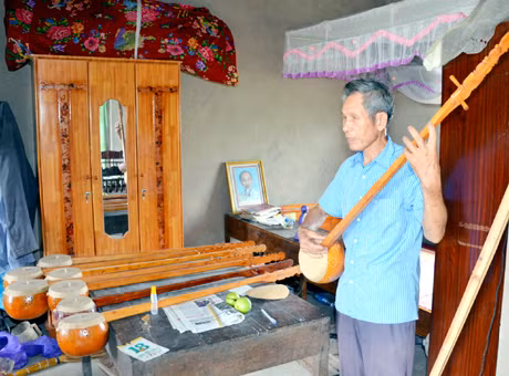 Ông Lương Thiêm Phú căng dây, thử tiếng cho những cây tính tẩu ông vừa hoàn thành.