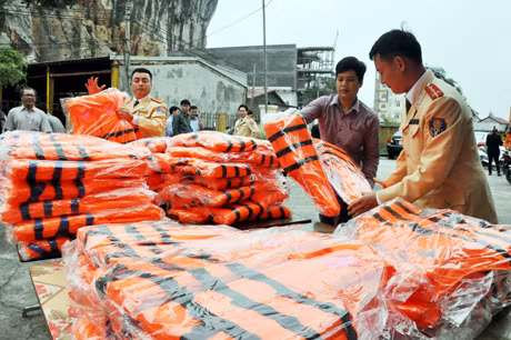 Cán bộ Phòng CSGT đường thuỷ Công an tỉnh trao tặng áo phao cứu sinh cho ngư dân nghèo.