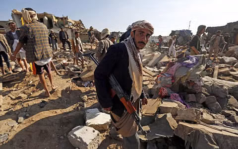 Một phiến quân Houthi đứng bên đống đổ nát được cho là do máy bay Mỹ gây ra (ảnh: EPA)